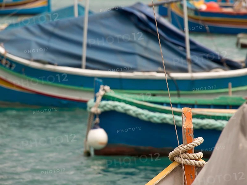 Several boats are quietly moored in the clear waters of a harbour, many colourful fishing boats in a harbour in the Mediterranean, Marsaxlokk, malta