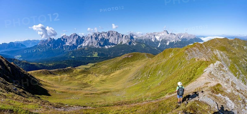Mountaineers on a hiking trail between green mountain meadows on a mountain ridge, mountain panorama, view of rocky mountain peaks of the Sesto Dolomites, Carnic Main Ridge, Carnic High Trail, Carnic Alps, Carinthia, Austria, Europe