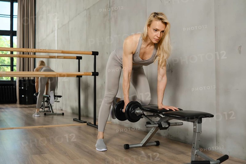 Middle-aged woman training with dumbbells in the gym