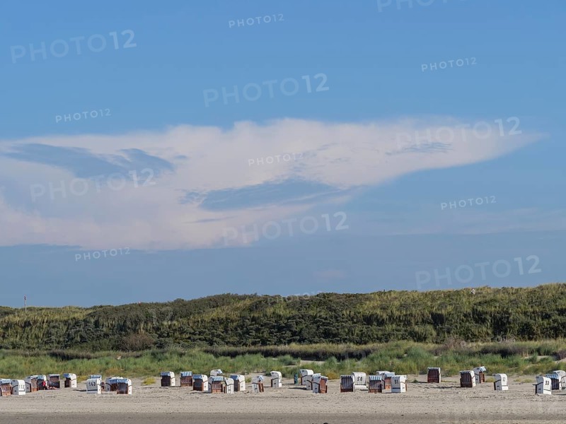 Beach with many beach chairs in front of large dunes, impressive cloud formation in the sky, dunes and beach at the sea with dune grass and beach chairs in front of blue sky, Spiekeroog, Germany, Europe