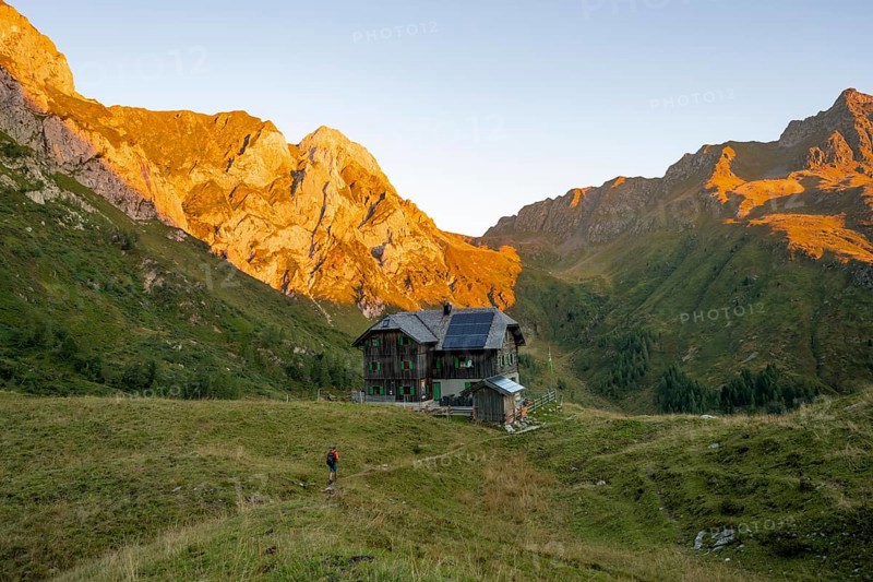 Alpine club hut, Hochweisssteinhaus mountain hut, mountain landscape with green mountain meadows and rocky peaks at sunrise, alpenglow, Carnic High Trail, Carnic Main Ridge, Carnic Alps, Carinthia, Austria, Europe