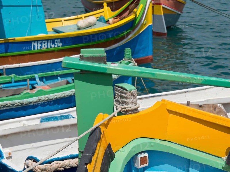 Colourful boats moored side by side at the pier in the clear waters of a harbour, many colourful fishing boats in a harbour in the Mediterranean, Marsaxlokk, malta