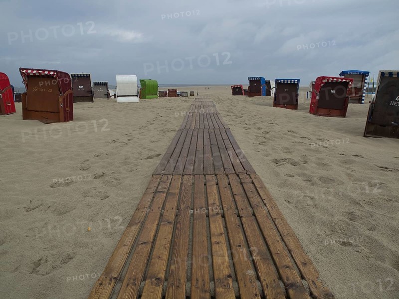 A wooden walkway leads through the sand, lined with beach chairs under a cloudy sky, beach chairs and beach tents by the sea under a cloudy sky, boardwalk in the sand, Borkum, germany