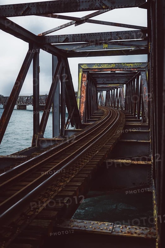 Rusty railway bridge with lake in the background. Cloudy day over Tauranga, New Zealand, Oceania