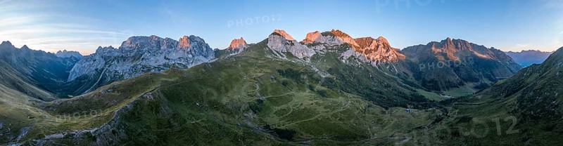 Alpine club hut, mountain landscape with green mountain meadows and rocky peaks at sunrise, alpenglow, Carnic High Trail, Carnic Main Ridge, Carnic Alps, Carinthia, Austria, Europe