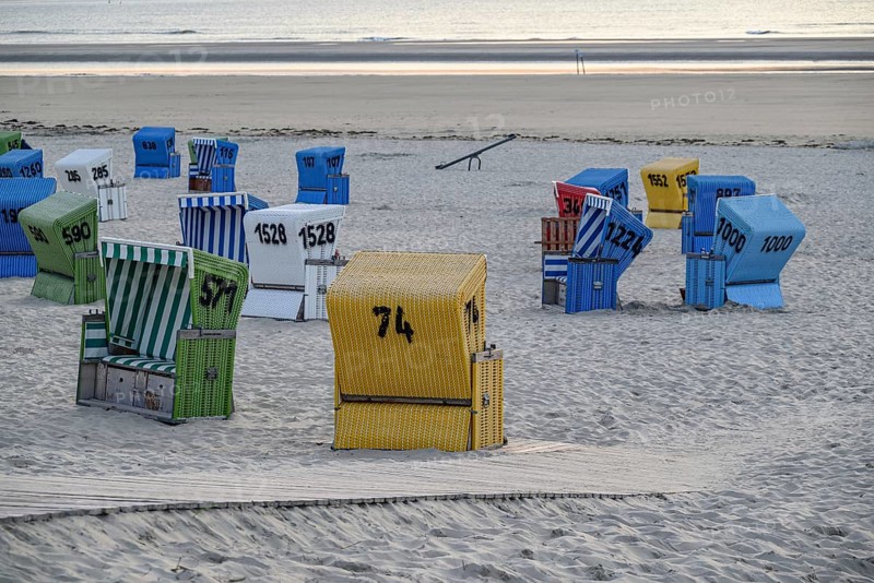 A quiet and relaxing beach evening with colourful beach chairs, a wooden walkway and soft sand, lots of colourful beach chairs on a balmy summer evening by the sea, langeoog, germany
