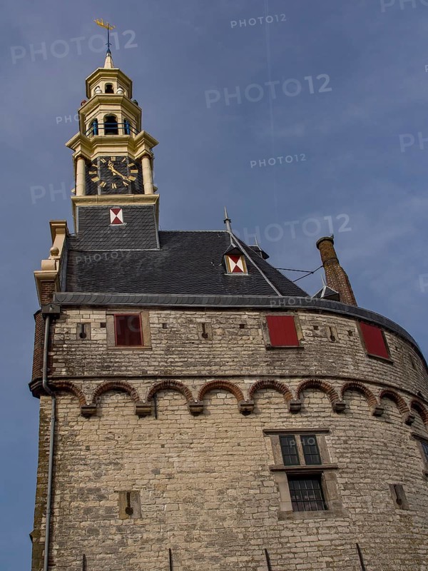 Historic stone clock tower with round superstructure in front of a blue sky, tower with a golden top and a large clock in front of a blue sky, hoorn, the netherlands