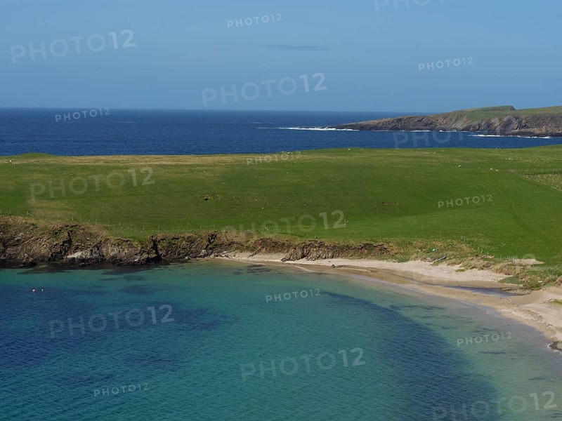Green grassy landscape along a calm bay with clear blue water under a wide sky, golden beach with green meadows on a deep blue sea with blue sky, lerwick, shetland, Scotland, United Kingdom, Europe