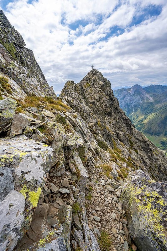 Narrow mountain path, rocky pointed summit of the Raudenspitze or Monte Fleons, with summit cross, Carnic Main Ridge, Carnic Alps, Carinthia, Austria, Europe
