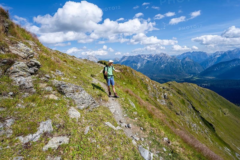 Mountaineer on a hiking trail on a grassy mountain slope, idyllic mountain landscape with green mountain meadows, descent from Baerenbadegg, Carnic High Trail, Carnic Main Ridge, Carnic Alps, Carinthia, Austria, Europe