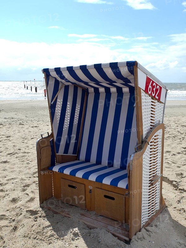 A single blue and white beach chair on the beach with the sea in the background and a cloudy sky, blue and white striped beach chairs on the beach, Norderney, Germany, Europe
