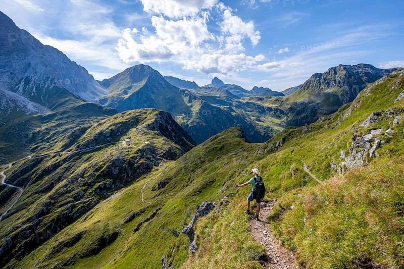 Mountaineer on a hiking trail on a grassy mountain ridge, idyllic mountain landscape with green mountain meadows, descent from Baerenbadegg, Carnic High Trail, Carnic Main Ridge, Carnic Alps, Carinthia, Austria, Europe