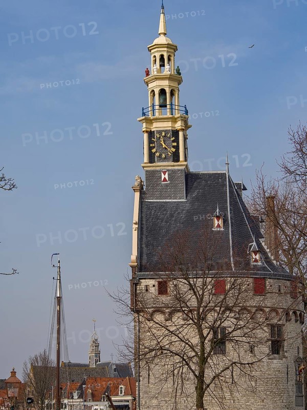 Historic clock tower with a view of the city and sailing boats against a blue sky, tower with a golden spire and a large clock against a blue sky, hoorn, the netherlands