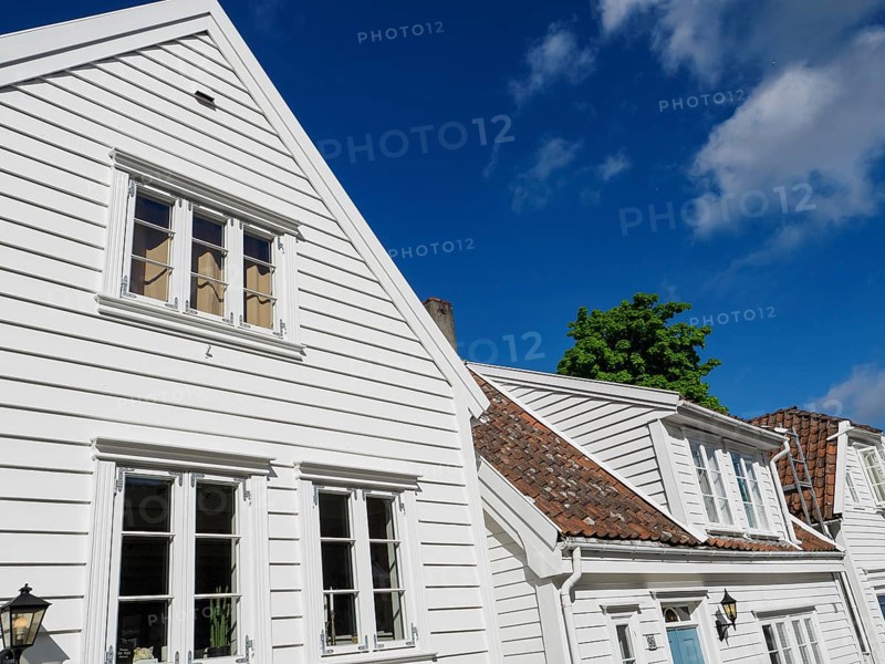 White wooden houses with windows and gutters under a clear blue sky in the sunshine, white wooden houses with green trees and flowers against a blue sky, Stavanger, Norway, Europe