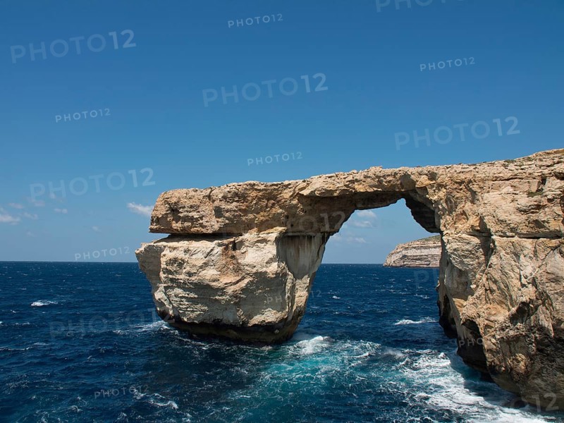Large rock arch towers over the sea, surrounded by cliffs and under a clear sky, many historic windmills by a river in the middle of fields, Kinderdijk, Netherlands