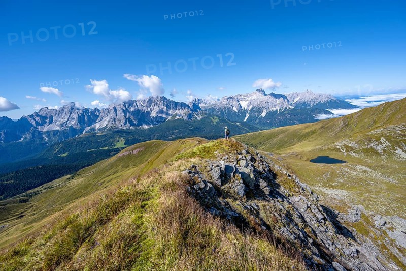 Mountaineers on a hiking trail between green mountain meadows on a mountain ridge, mountain panorama, view of rocky mountain peaks of the Sesto Dolomites, Carnic Main Ridge, Carnic High Trail, Carnic Alps, Carinthia, Austria, Europe