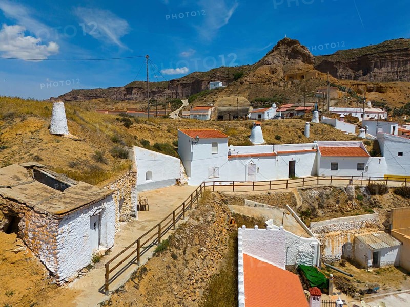 Houses and buildings on a rocky hill with blue sky and fences, cave dwellings, Gorafe, Guadix, Granada, Andalusia, Spain, Europe