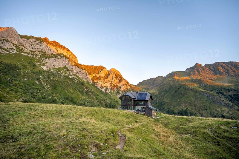Alpine club hut, Hochweisssteinhaus mountain hut, mountain landscape with green mountain meadows and rocky peaks at sunrise, alpenglow, Carnic High Trail, Carnic Main Ridge, Carnic Alps, Carinthia, Austria, Europe