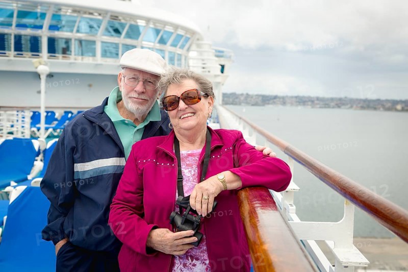 Senior adult couple enjoying the view from their passenger cruise ship with their bonoculars