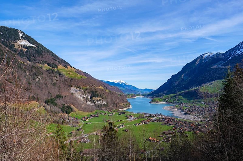 View of a valley with a lake and a village surrounded by mountains under a blue sky, Lungern, Obwalden, Switzerland, Europe