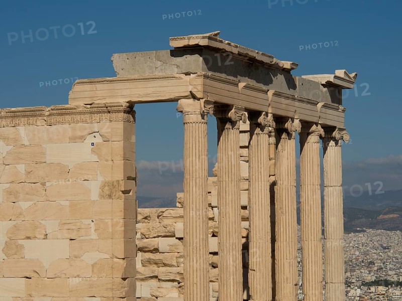 Ancient marble columns in a ruin with a part of the city in the background under a clear sky, historical columns and ruins at an ancient site against a blue sky, Athens, Greece, Europe