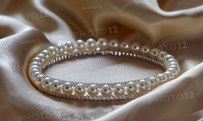 A pearl bangle bracelet with intricate detailing laid out on a smooth satin material background AI generated