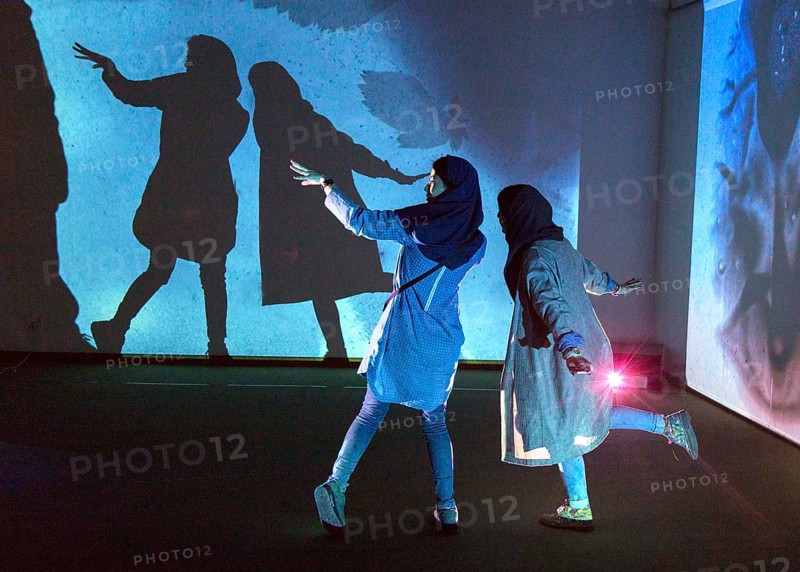 Two woman look at an exhibition by the German artist Otto Piene in Tehran on 6 April 2015 and make shadow plays in the light installation, Tehran, Iran, Asia