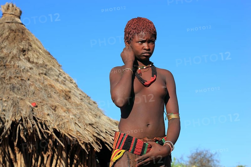 South Ethiopia, Omo region, young woman of the Hammer people standing in front of a round hut, dwelling, Ethiopia, Africa
