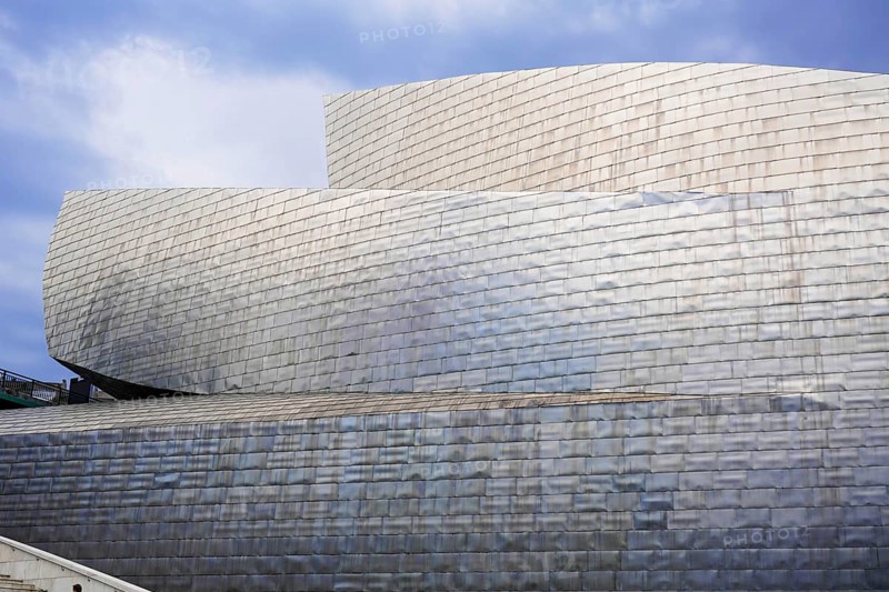 Guggenheim Museum Bilbao on the banks of the Nervion River, architect Frank O. Gehry, Bilbao, View of the metallic facade of a modern museum with curved lines and a cloudy sky in the background, Guggenheim Museum, architect Frank O. Gehry, Bilbao, Bizkaia Province, Basque Country, Spain, Europe