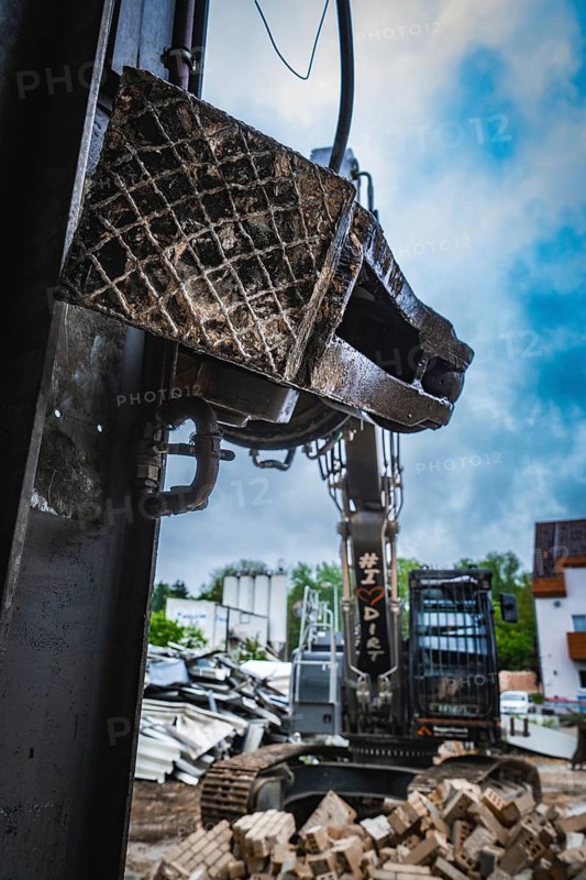 Close-up of the grab of an excavator in the foreground, working surrounded by rubble under a cloudy sky, demolition, Saarbruecken, Germany, Europe