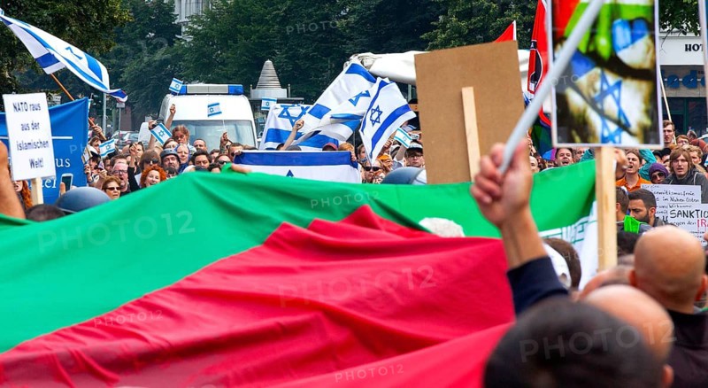 Protesters of the Al Quds demonstration with a large Palestinian flag march past the pro-Israel demonstrators. Over 1000 people demonstrate against Israel's military attacks in the Gaza Strip, 25 July 2014, Berlin, Germany, Europe