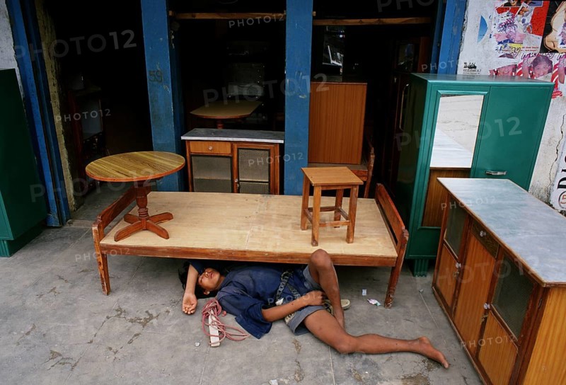 Young man sleeping on the ground in the shop where he is working, Kathmandu, Nepal, Asia