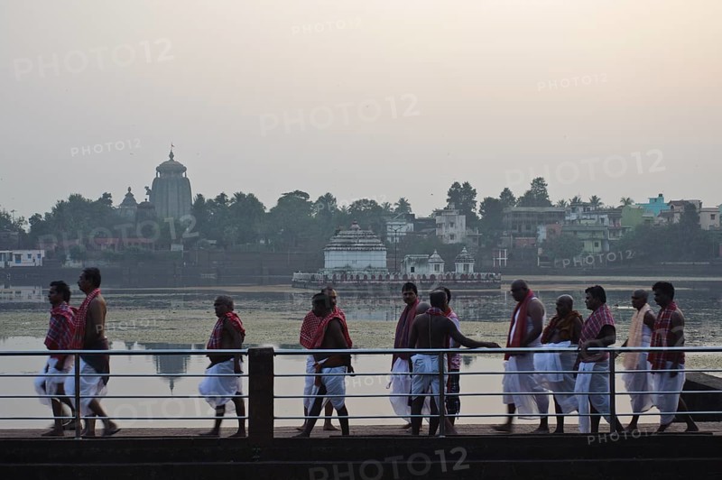 High caste hindus are walking along the lake Bindu, brahmins have performed a hindu ritual, Lingaraj temple in the background, Bhubaneswar, India, Asia