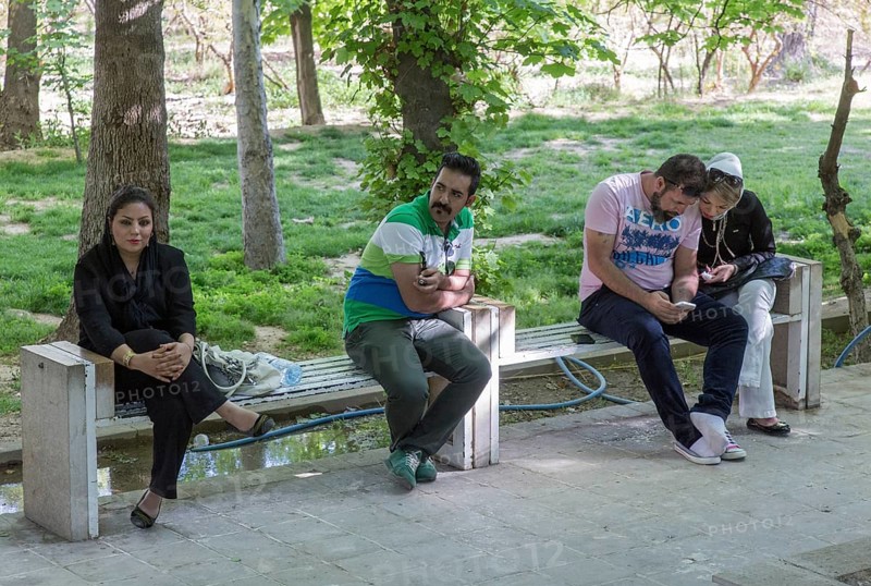 A young Iranian couple an Iranian woman and an Iranian man on 03/04/2015 sitting on a bench in the tropical garden in Shiraz, Shiraz, Iran, Asia