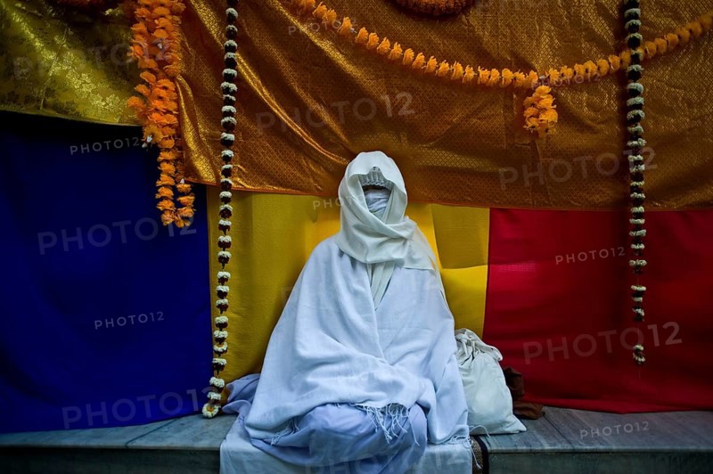 Asian female pilgrim meditating in the Mahabodhi temple, buddhist pilgrimage site at Bodhgaya, Bihar, India. The Mahabodhi temple is the place where the Buddha has attained enlightenment. It is now a major pilgrimage destination for buddhists from all over the world