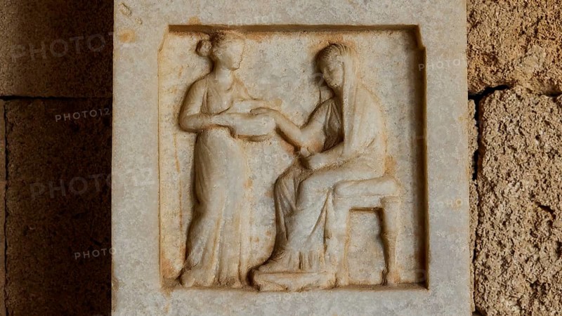 Funerary stele from Obastis, Diphros, Alabastron, seated deceased woman and standing servant, A stone relief shows two figures, one seated and one standing, in an antique style, Interiors, Archaeological Museum, Old Town, Rhodes Town, Rhodes, Dodecanese, Greek Islands, Greece, Europe