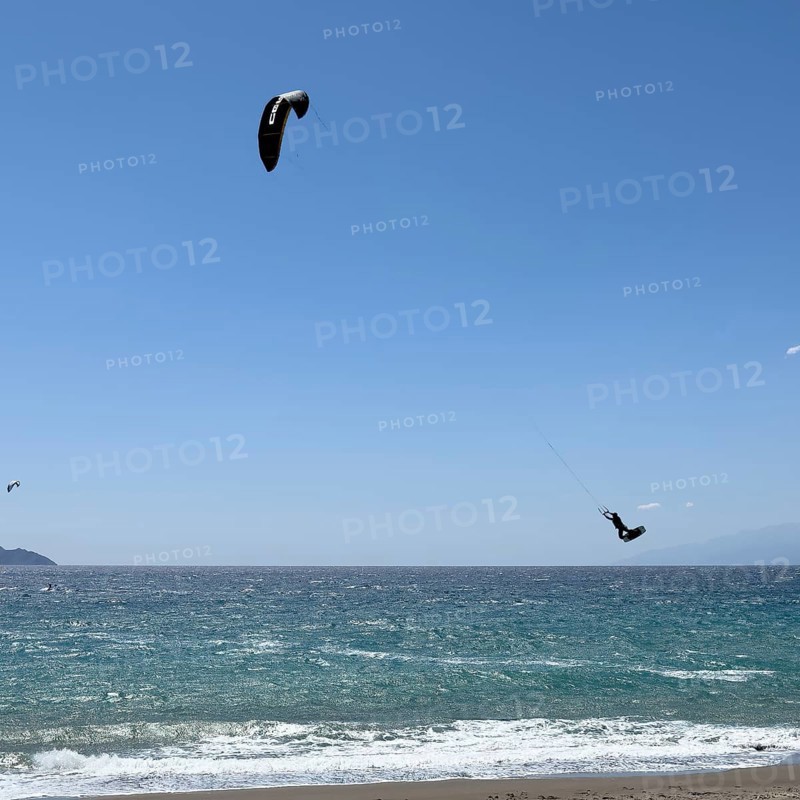 Kitesurfer Kitesurfer takes off in strong wind and waves rough sea moving sea flies with inflated sail high through the air, Kalamaki, Crete, Greece, Europe