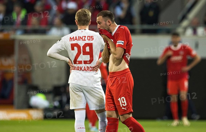 Football match, Jonas FOeHRENBACH 1.FC Heidenheim right, visibly exhausted, dries his wet and sweaty mouth with the front part of his jersey, Jonathan Michael BURKARDT SV Mainz 05 left from behind holding his arms left and right supporting him in the tallie, football stadium Voith-Arena, Heidenheim