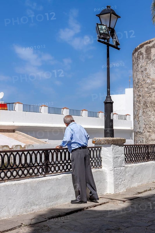 Senior citizen looking over a parapet on the street, Vejer, Andalusia, Spain, Europe