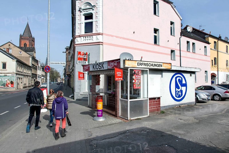 A pedestrian walks past a kiosk in Gelsenkirchen with a large S04 logo of FC Schalke 04 on it, Gelsenkirchen