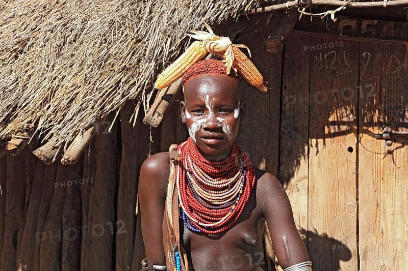 South Ethiopia, Omo region, among the Karo people, young woman, girl with jewellery and face painting sitting in front of a hut, Ethiopia, Africa