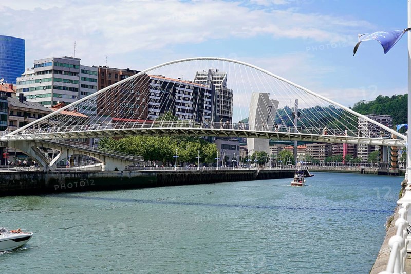 Pedestrian bridge Zubizuri, White bridge, Bilbao, Modern bridge over a river Nervion, with skyscrapers in the background, Boat in the water, Old town, Bilbao, Basque Country, Spain, Europe