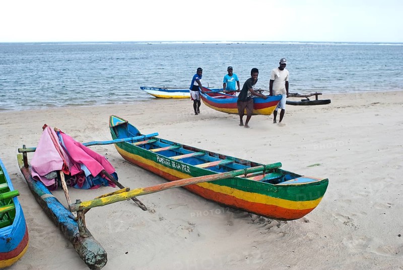 Beach attendants carrying a canoe to take it away from the sea, beach on the Indian ocean, Foulpointe, Madagascar, Africa