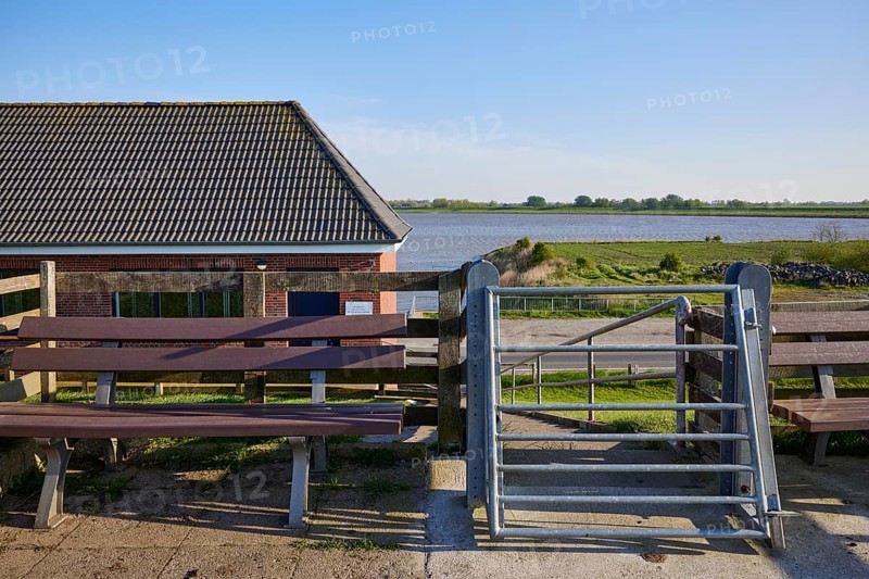 Self-closing door and bench on the dyke crest near Tetenbuell, Nordfriesland district, Schleswig-Holstein, Germany, Europe