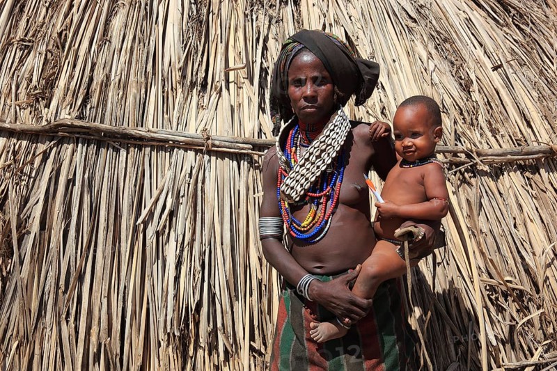 South Ethiopia, in a village of the Arbore or Erbore people at Lake Stefano, young woman with baby in front of her hut, Ethiopia, Africa
