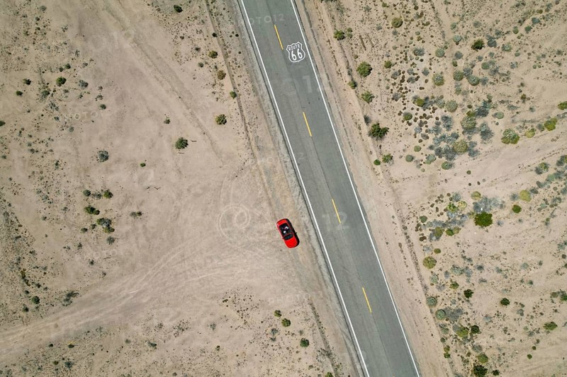 Drone shot of Route 66 with Route 66 sign on the road and red Ford Mustang convertible, Mojave Desert, California