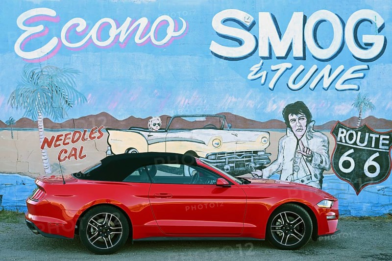 Red Ford Mustang convertible in front of mural with Elvis, Needles, California