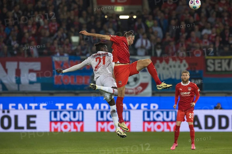 Football match, Jonas FOeHRENBACH 1.FC Heidenheim right in a spectacular aerial fight for the ball with Danny Vieira DA COSTA 1. FSV Mainz 05 left from behind, Jan-Niklas BESTE 1. FC Heidenheim watches the rather uncontrolled aerial fight in the background with his mouth open in amazement, football stadium Voith-Arena, Heidenheim