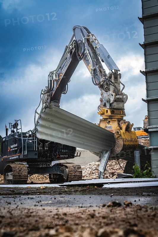 A large excavator lifts building materials on a construction site, the sky is cloudy and the surroundings look industrial, Demolition, Saarbruecken, Germany, Europe