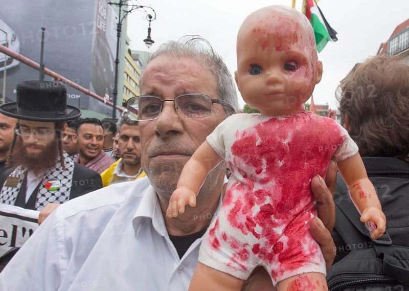 A Palestinian holds a doll coloured with red paint during the Al Quds demonstration in Berlin. Over 1000 people demonstrate against Israel's military attacks in the Gaza Strip, 25 July 2014, Berlin, Germany, Europe